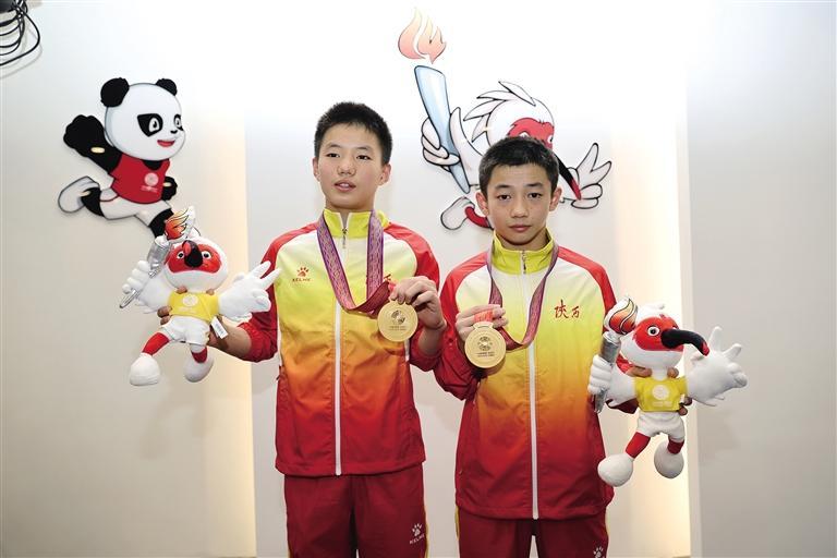 7月12日，白钰豪（右）、白钰鸣展示他们在十四运会跳水U14组比赛男子双人跳台决赛中获得的金牌。 陕西日报.jpeg